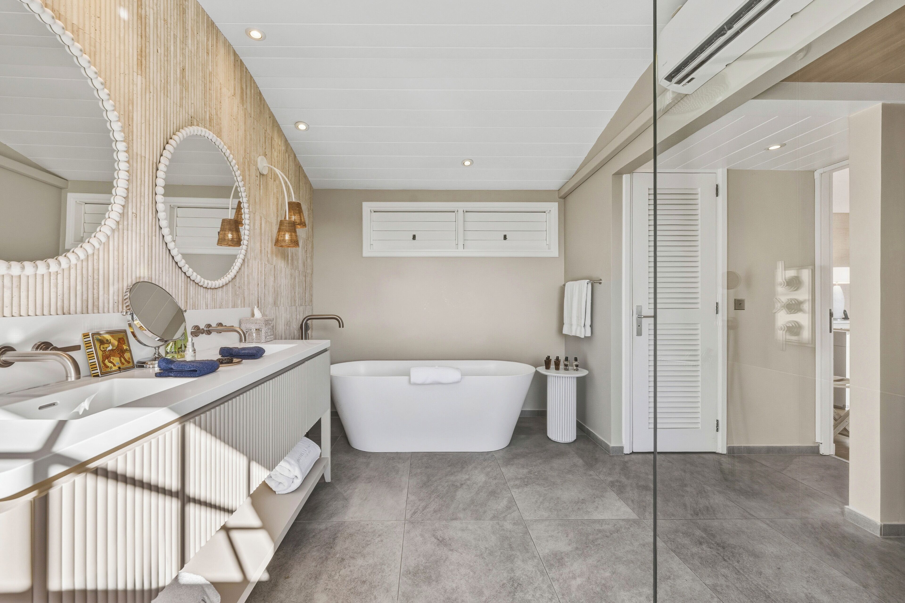 A modern bathroom with a freestanding bathtub, a large mirror, and a vanity with a sink and towel rack.
