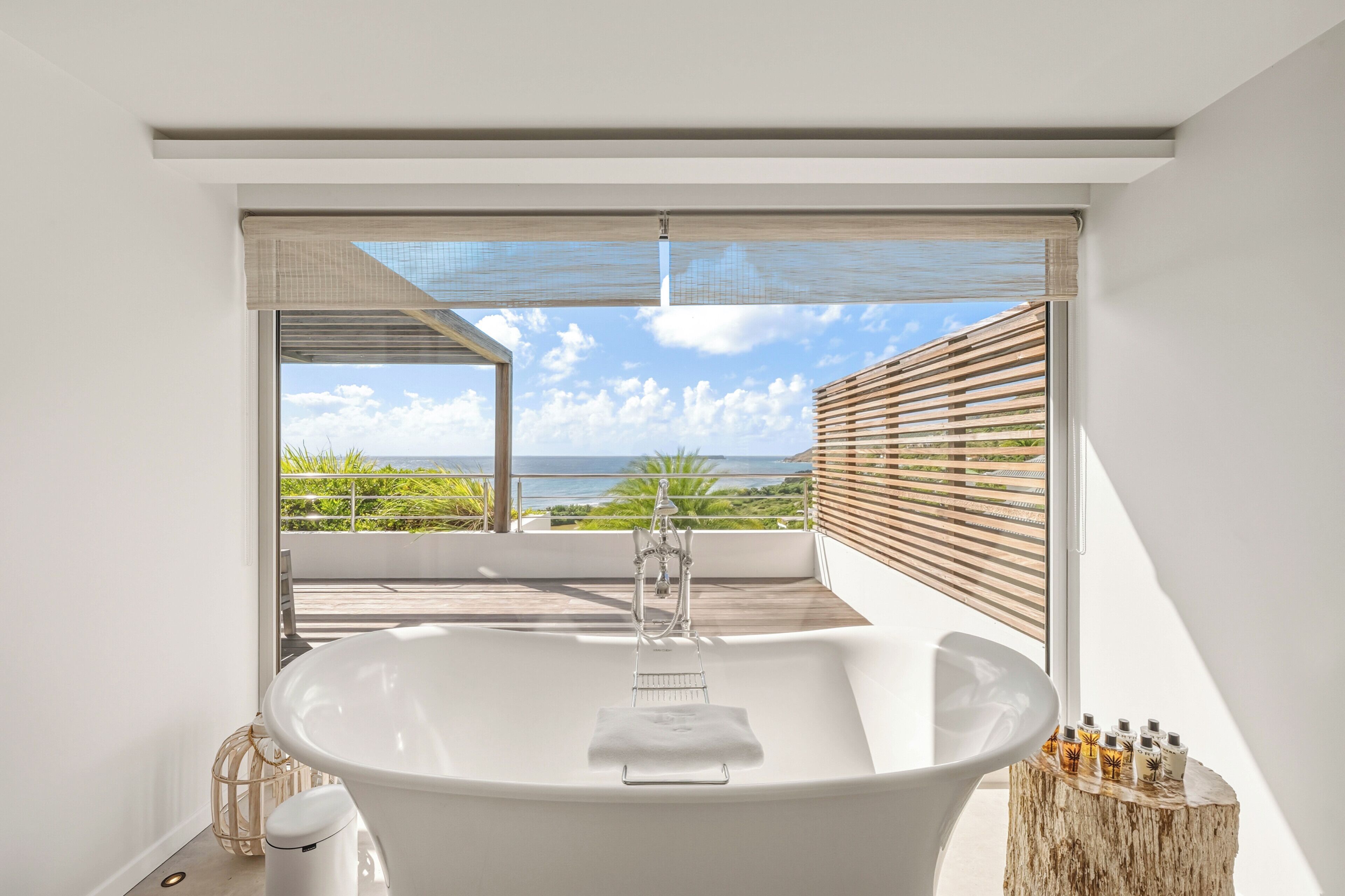 Ein modernes Badezimmer mit einer freistehenden Badewanne, einem weißen Waschbecken und Meerblick durch große Fenster.