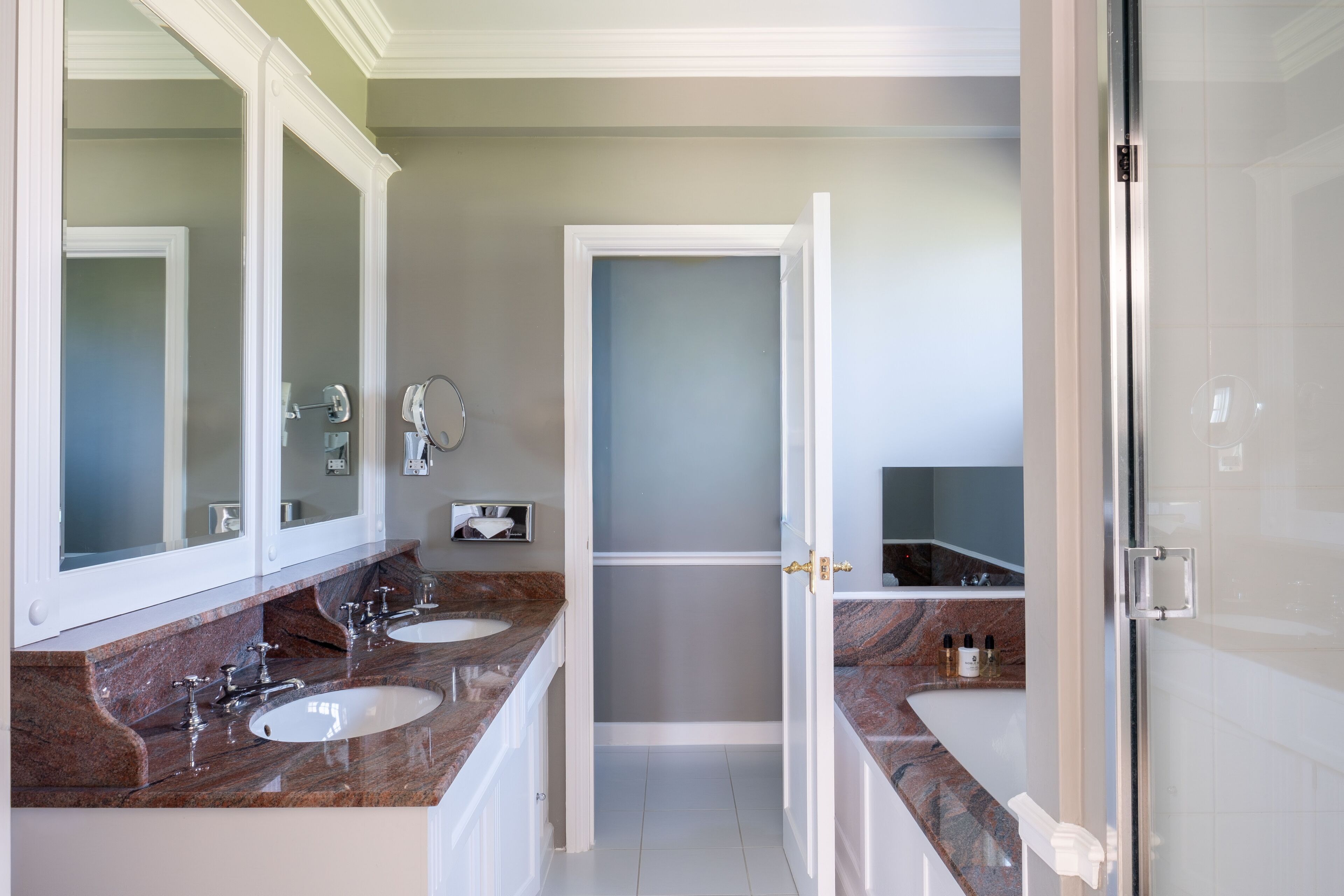 A bathroom with two sinks, a mirror, and a shower area.