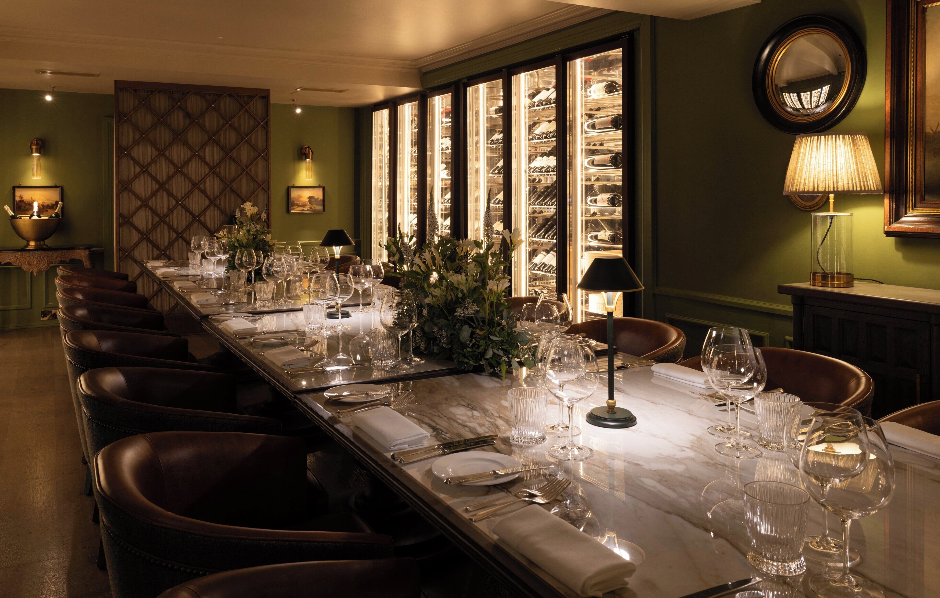 A long dining table set with chairs, a wine rack, and a mirror on the wall.