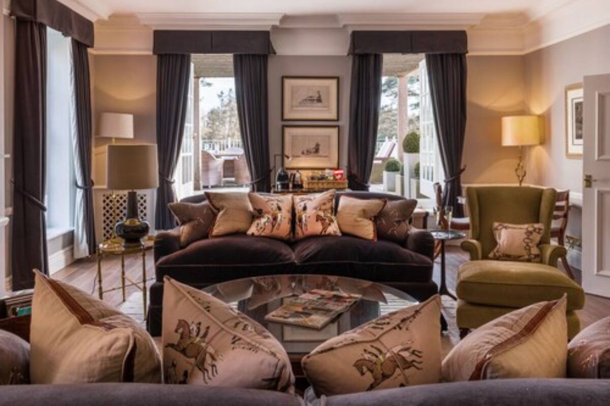 A spacious living room with a dark velvet sofa, multiple cushions, a coffee table, and a green armchair.