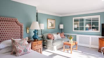Een kamer met een bed, een slaapbank, een tafeltje, een lamp en een spiegel.