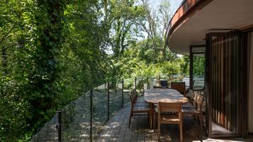An outdoor patio with a table and chairs, surrounded by a metal fence and lush greenery.