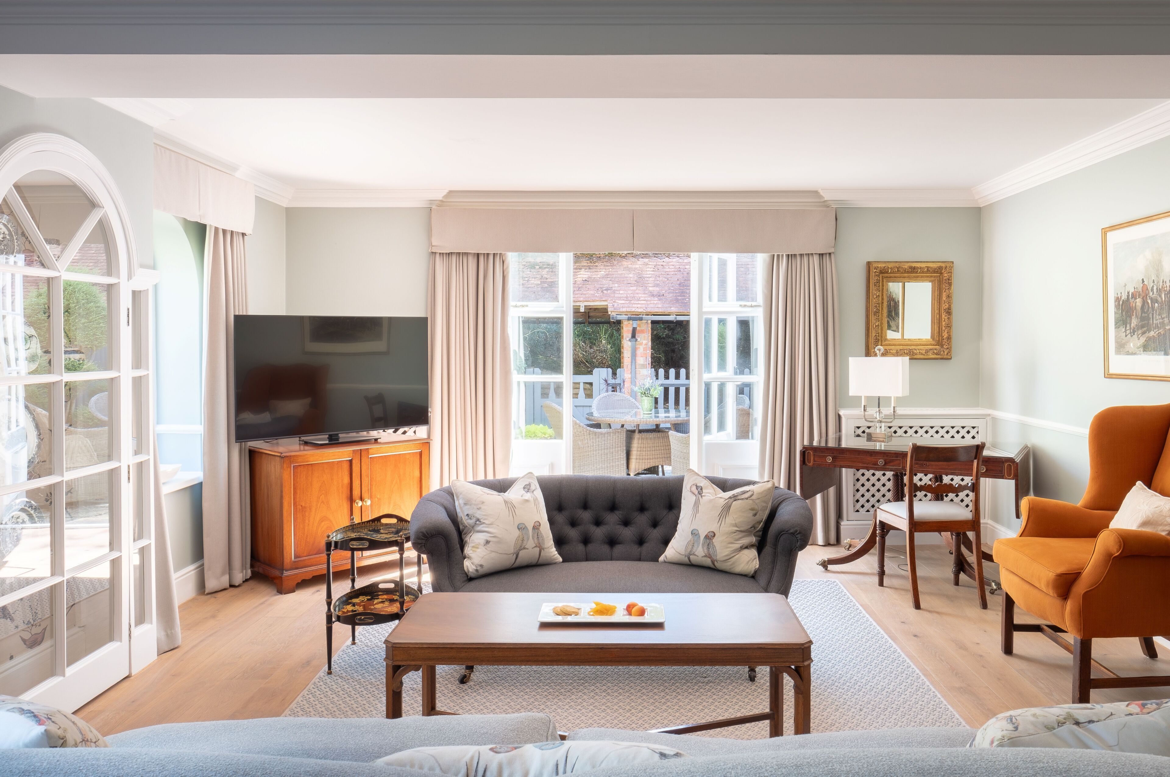 A living room with a sofa, coffee table, and a television. There is a dining area with a table and chairs.