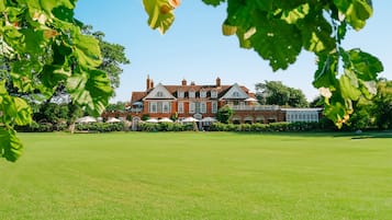 Stately building with a traditional facade, set amidst lush gardens and mature trees.