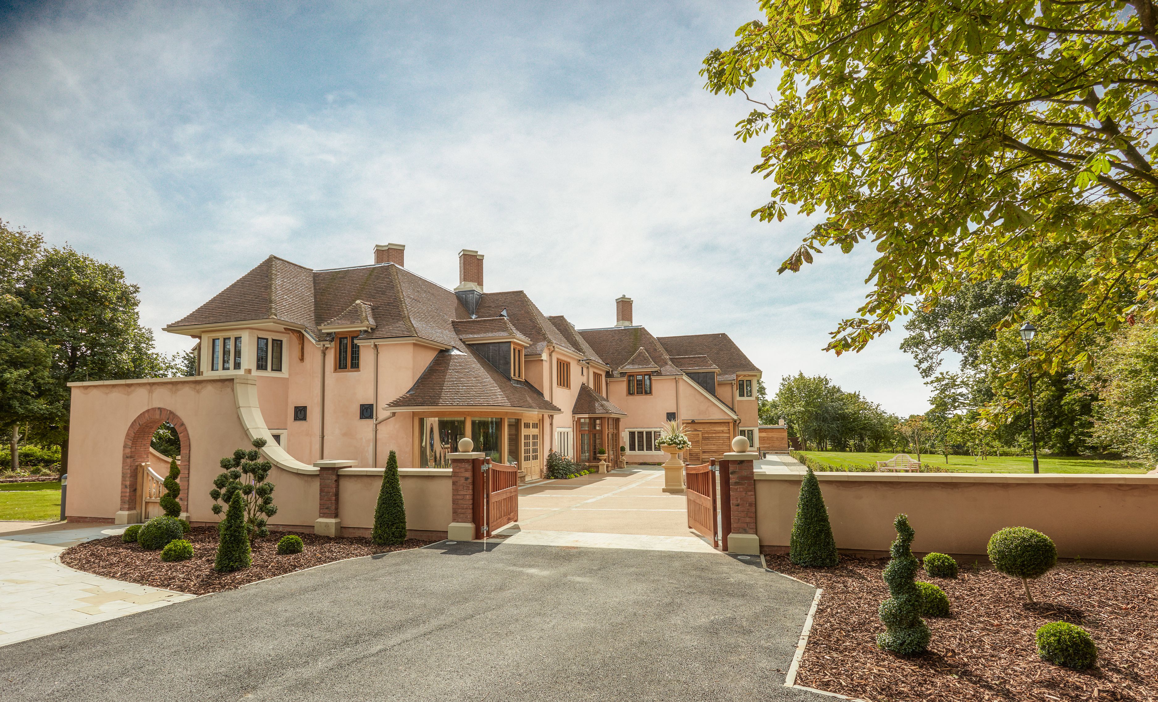 A large, multi-story house with a driveway leading to a gated entrance.