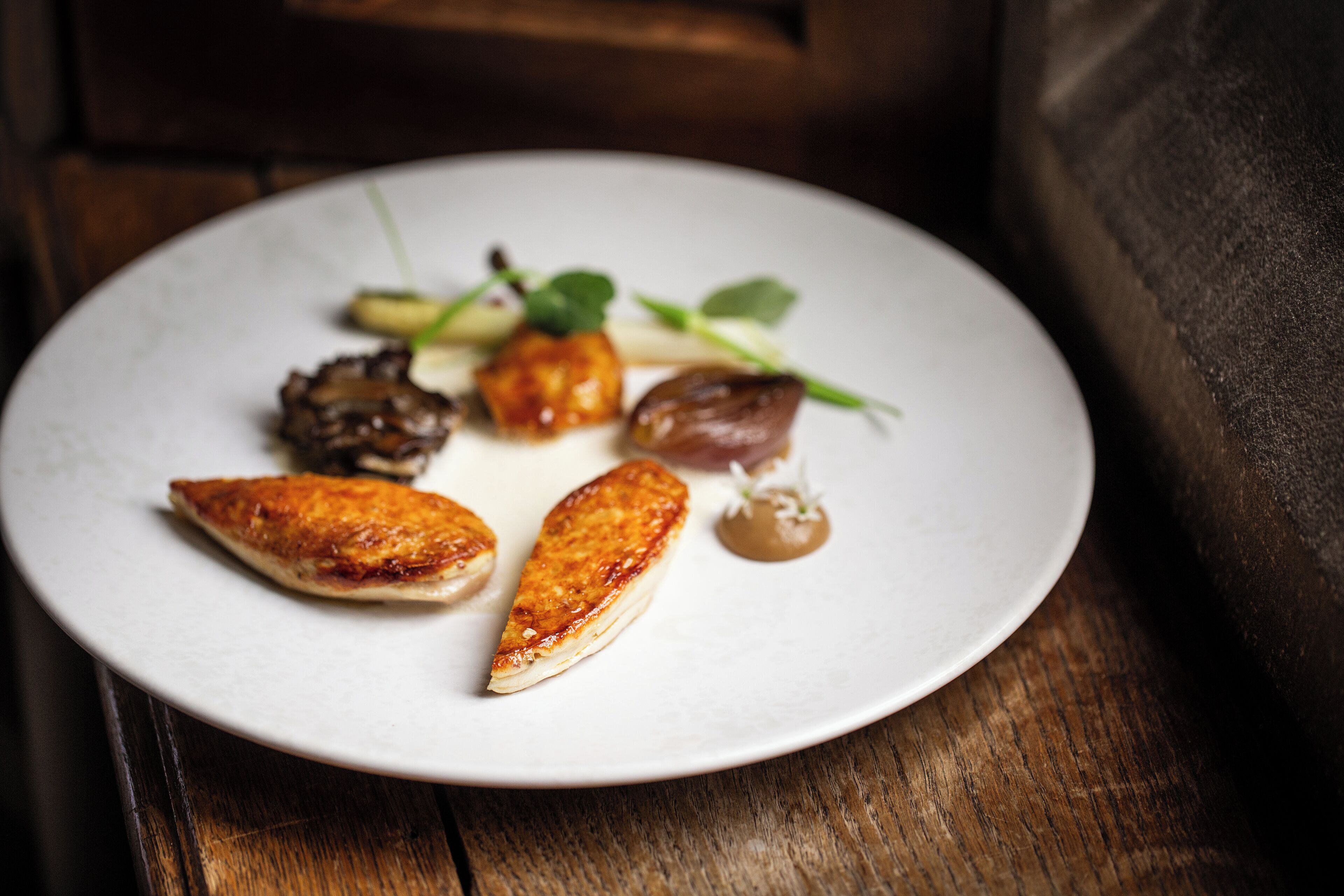 A white plate with various food items on a wooden table.