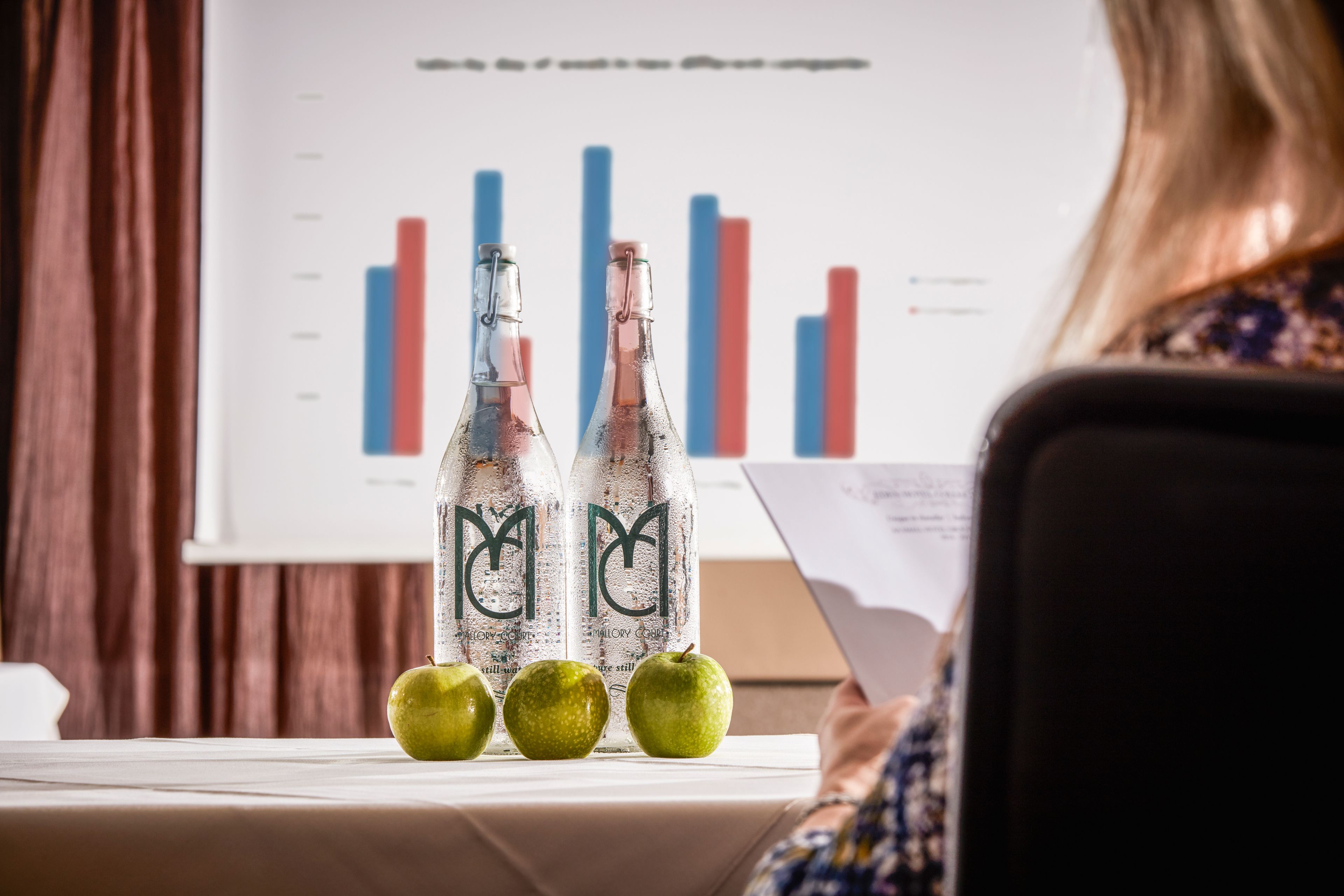 A table with two bottles and three apples.