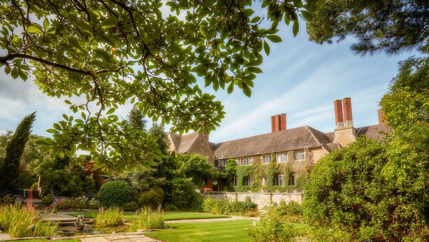 Un grand bâtiment historique doté d’un jardin bien entretenu, de sentiers en pierre et d’un étang.