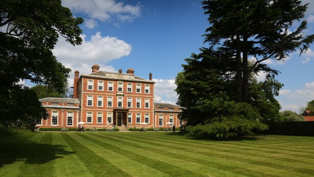 A large, multi-story building with a symmetrical facade, surrounded by well-manicured lawns and mature trees.
