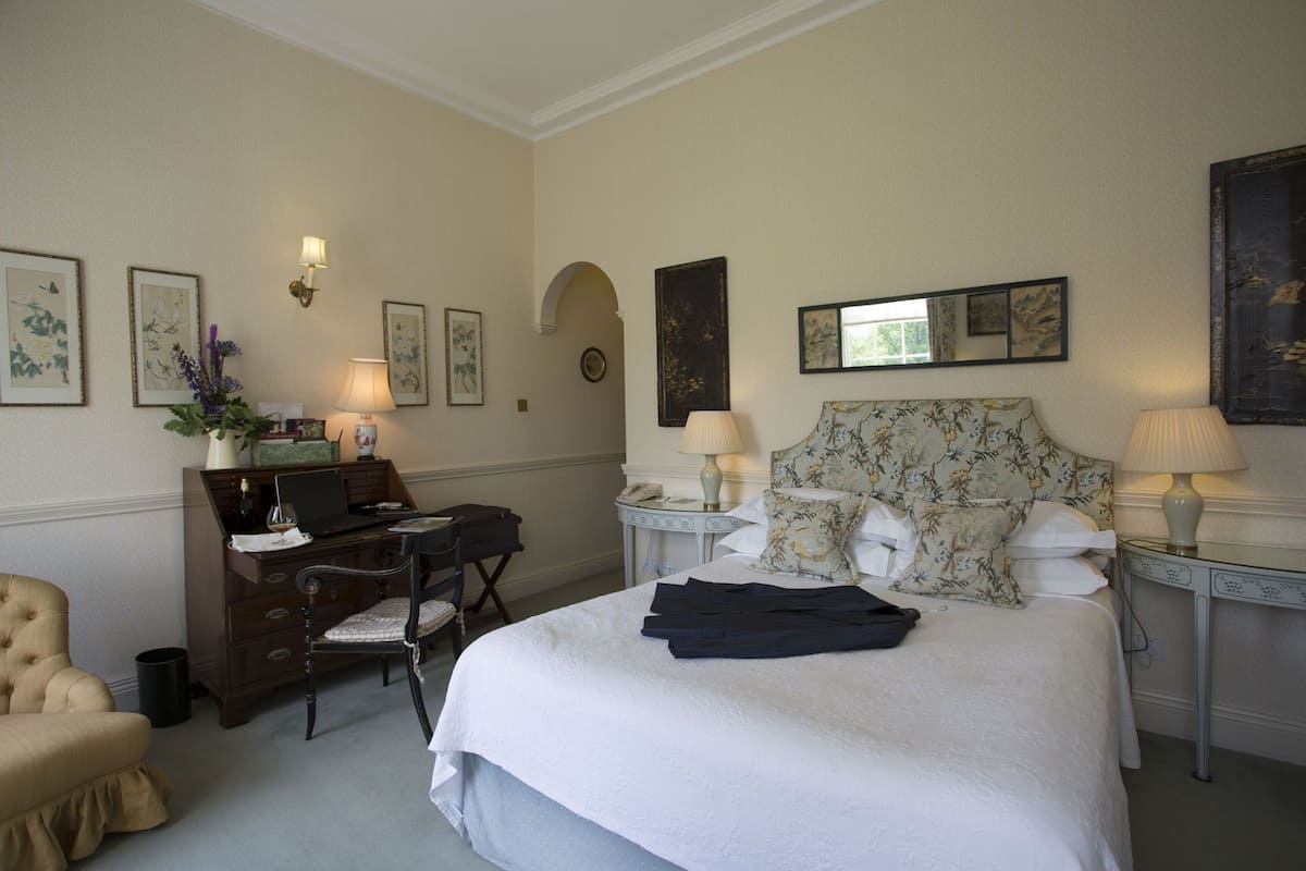 A hotel room with a bed, a desk, a chair, and a dresser.