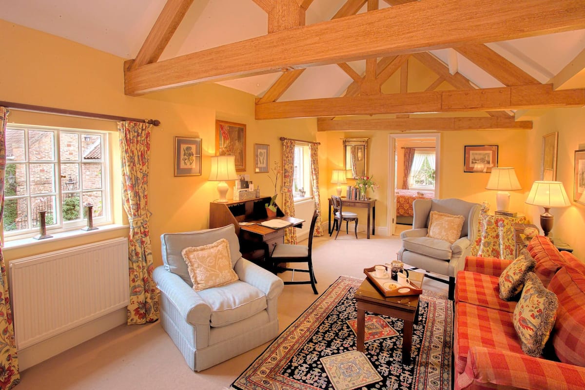A cozy living room with a fireplace, a dining area, and a kitchen in the background.