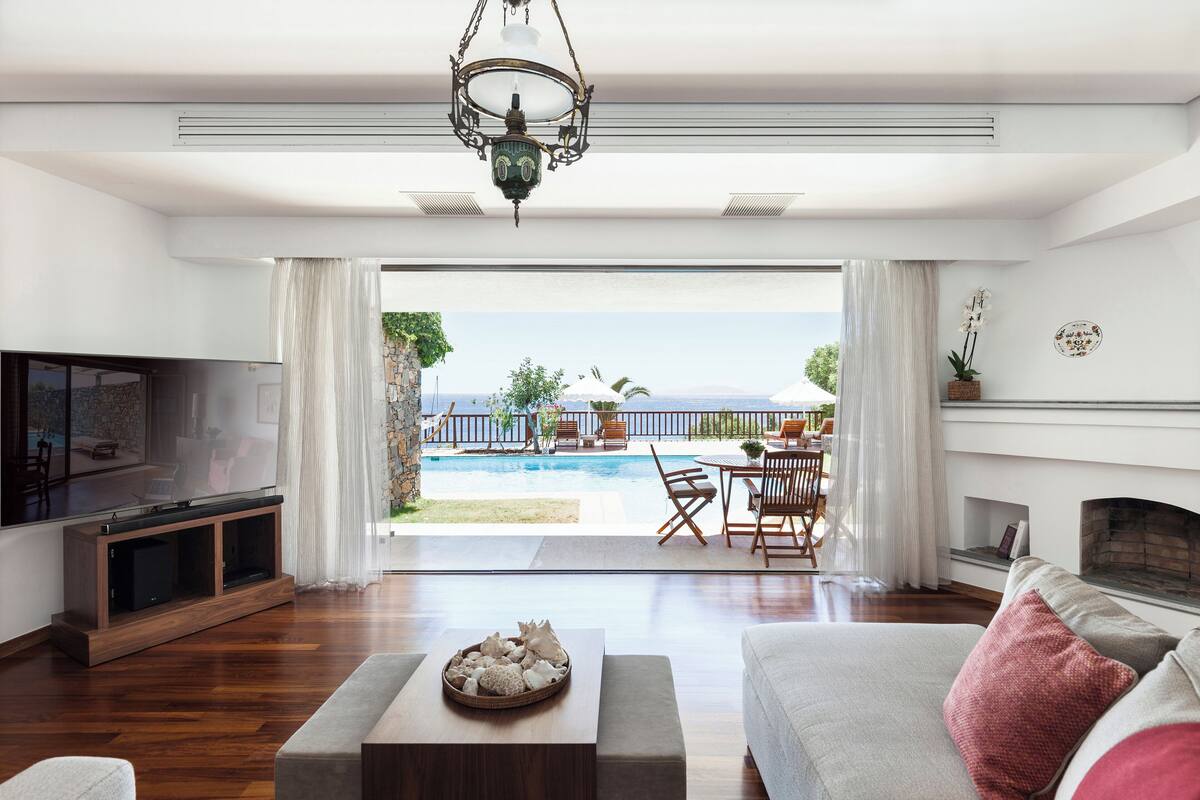 Ein modernes Wohnzimmer mit Fernseher, Kamin, Blick auf den Pool und Essbereich.