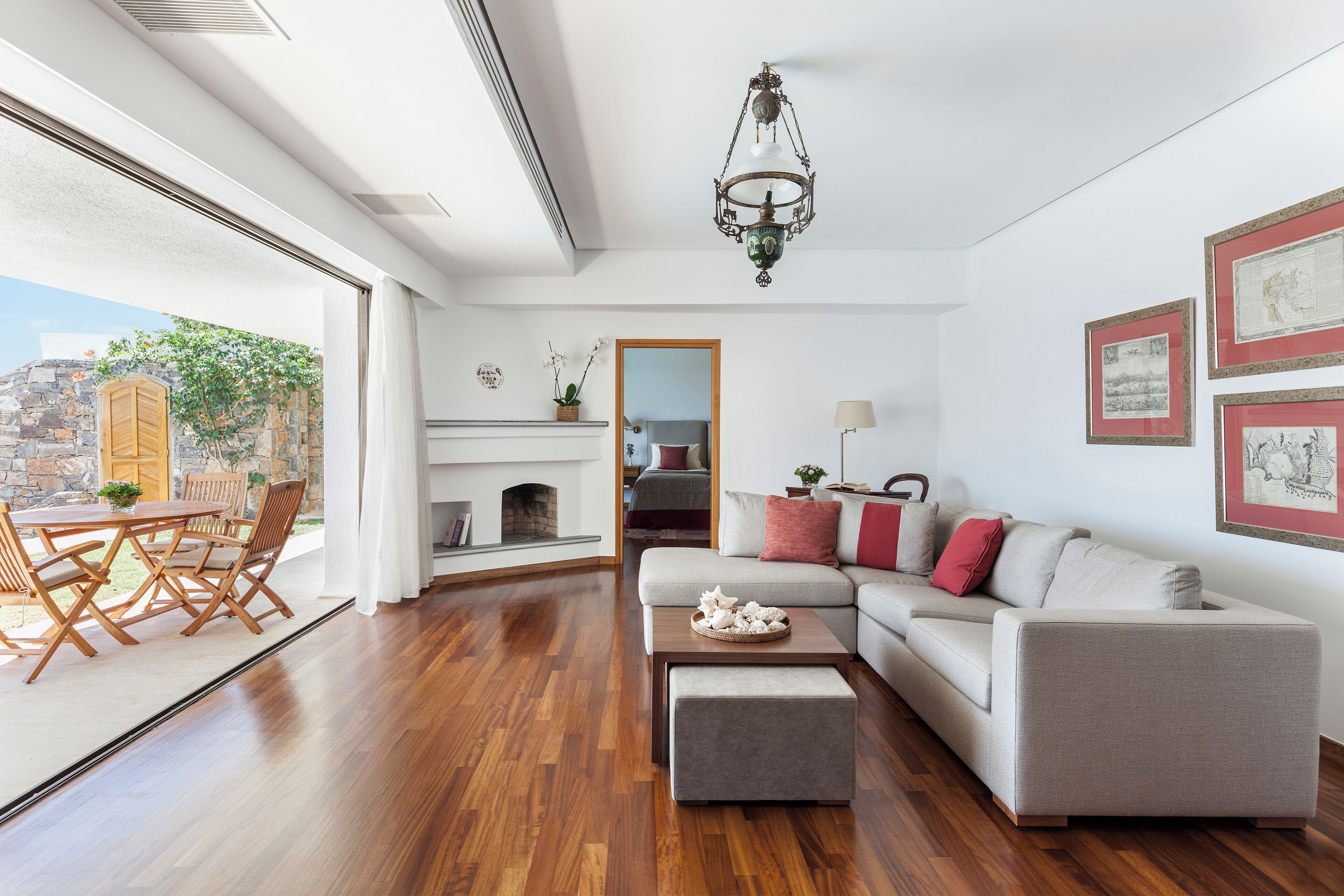 A spacious living room with a wooden floor, a gray sofa, a coffee table, and a fireplace.