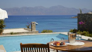 Vista de la piscina con una mesa preparada para una comida, un balde de metal y un vaso de agua.