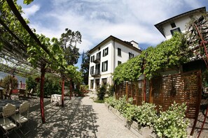 A courtyard with a gravel path, outdoor seating, and a building with balconies. - Il Sole di Ranco (Ranco)
