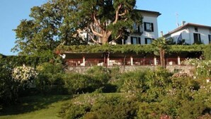 Un edificio a due piani con un grande albero di fronte.
