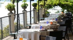 An outdoor dining area with round tables, chairs, and potted plants. - Il Sole di Ranco (Ranco)