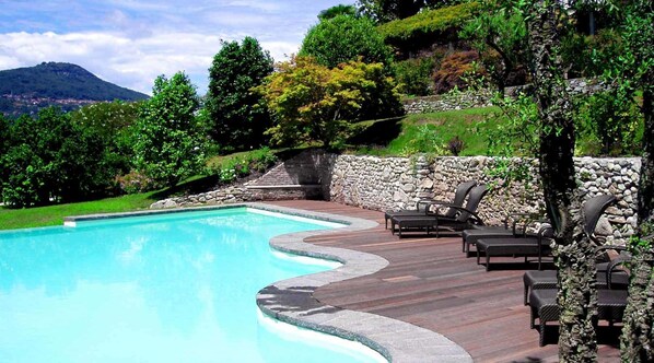 Una piscina al aire libre, sombrillas, tumbonas