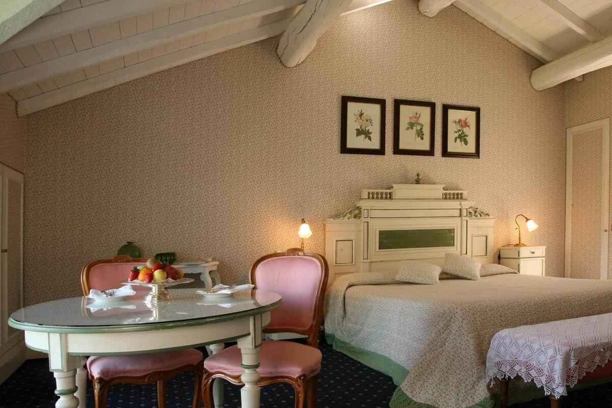 A bedroom with a bed, bedside table, lamp, and a round table with chairs.