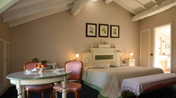 A bedroom with a bed, bedside table, lamp, and a round table with chairs.