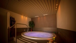 A spa area with a hot tub, steps leading to it, and a potted plant.