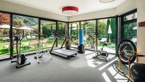 A gym with exercise equipment, large windows, and a view of the outdoors.