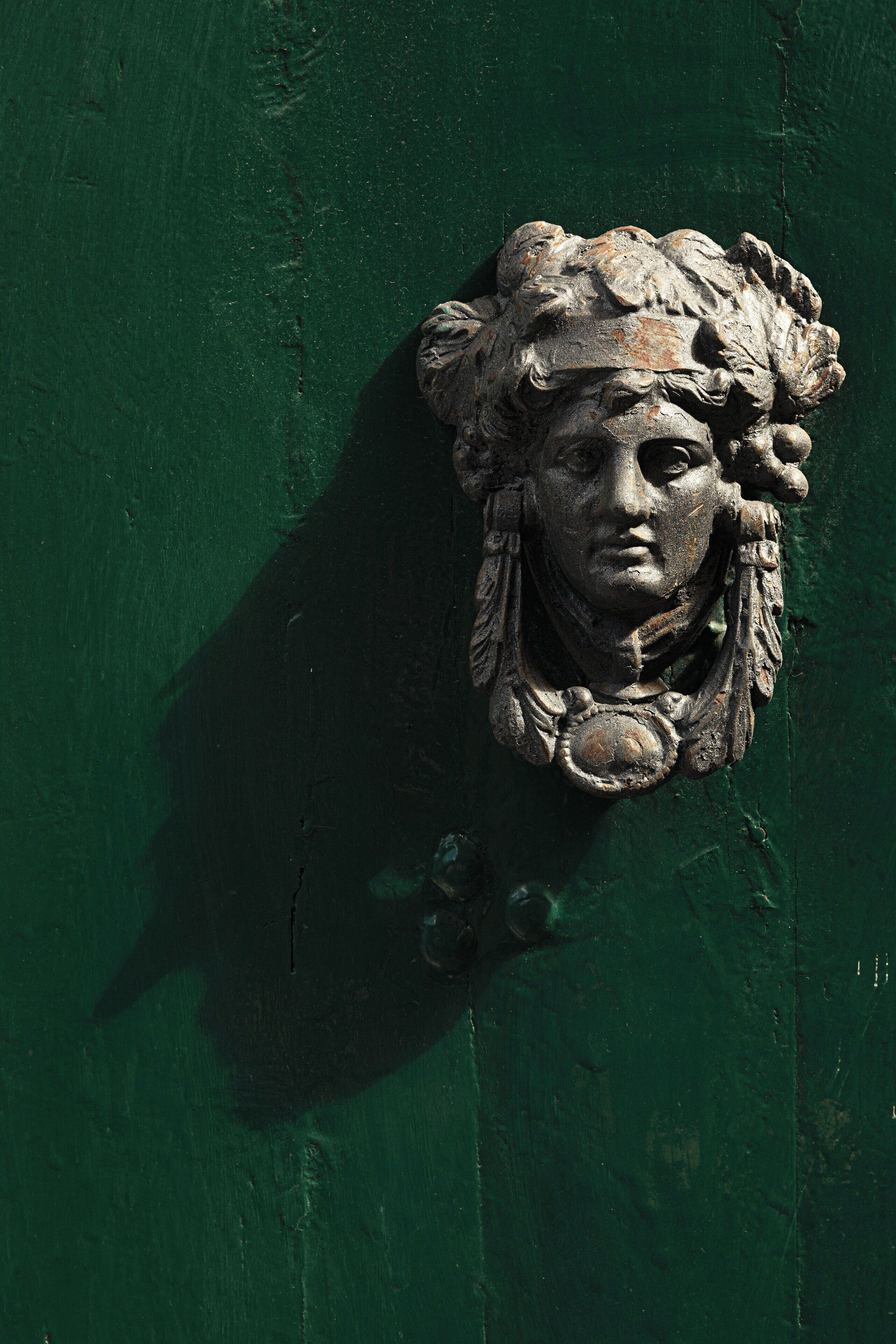 A green door with a classical relief sculpture.