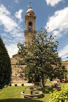 Un cortile con un campanile, un prato curato e posti a sedere all'aperto.