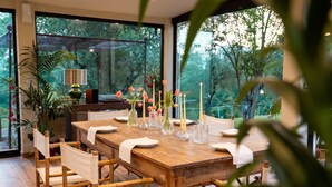 Un coin repas avec une table en bois dressée pour quatre personnes, entourée de chaises en bambou.