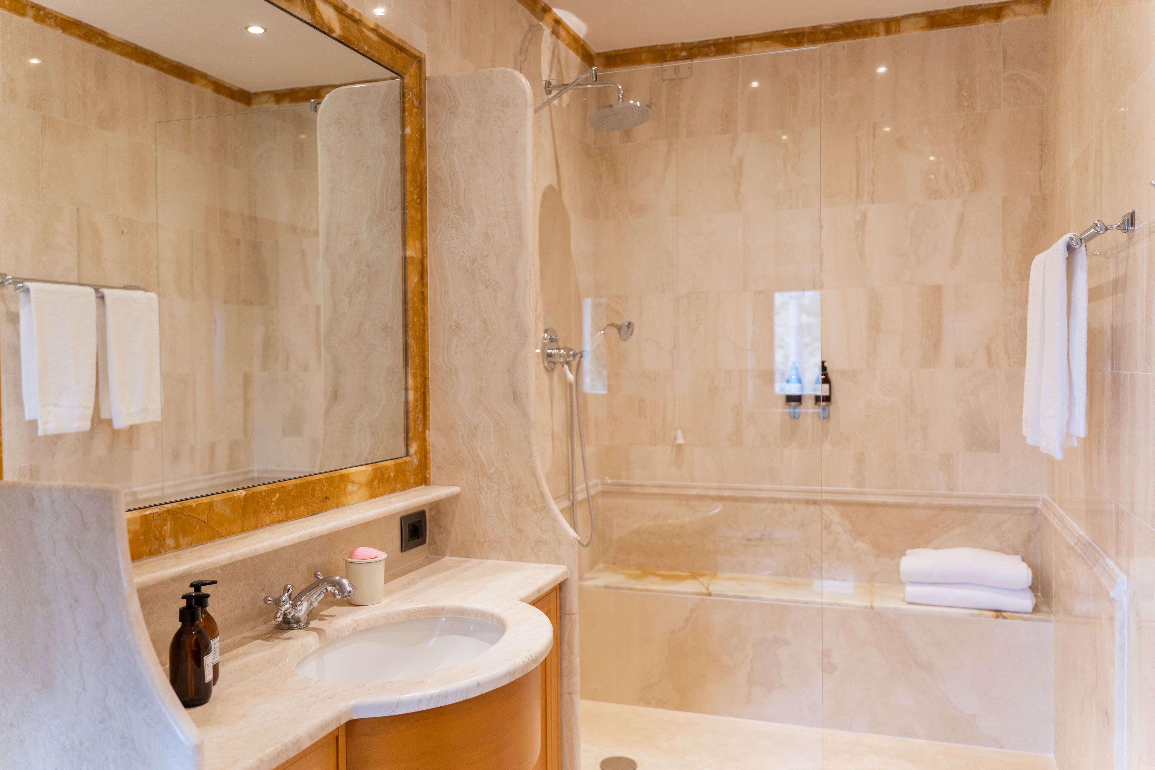 A modern bathroom with a marble sink, a large mirror, a shower, and a bathtub.