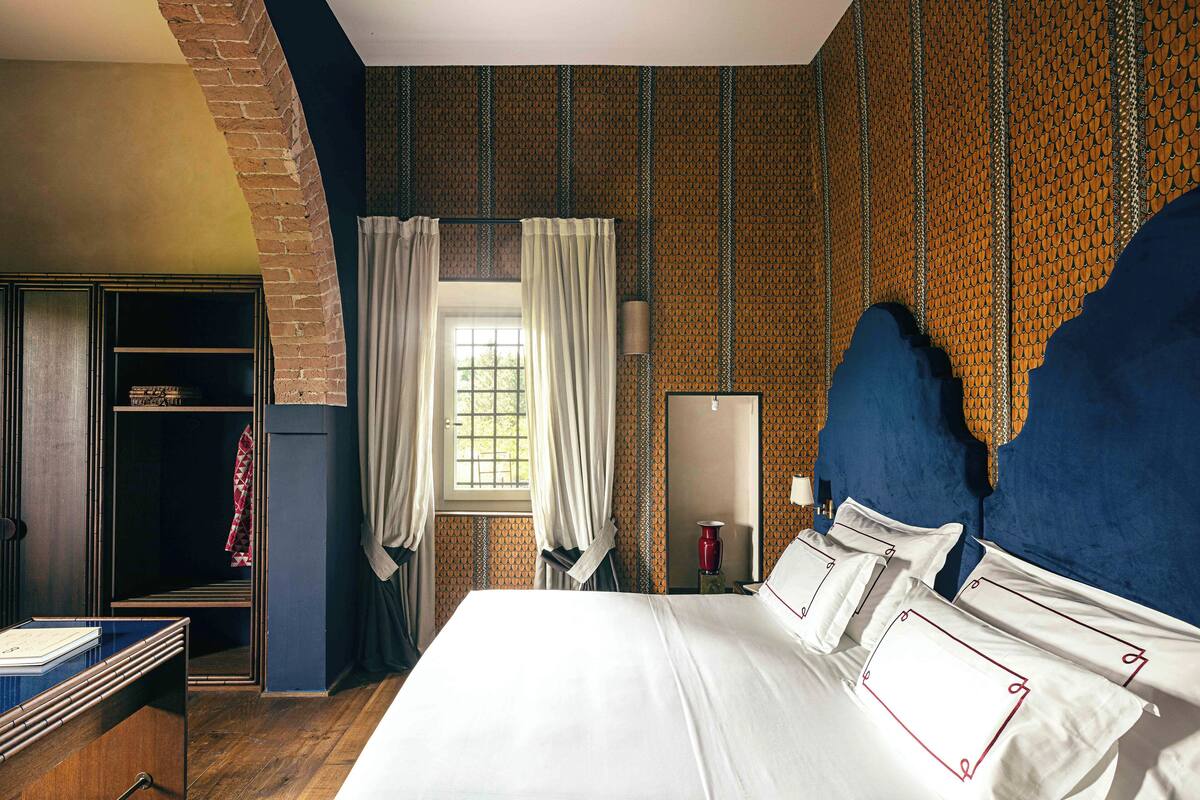 Habitación de hotel con una cama grande, un armario, un escritorio y una ventana con cortinas.