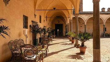 An outdoor courtyard with a tiled floor, arched ceilings, and potted plants.