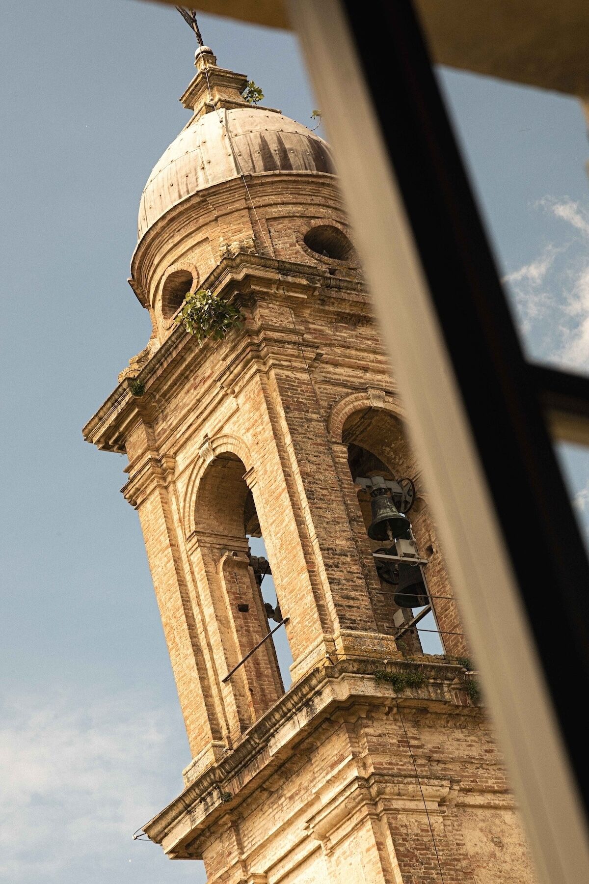A historic tower with a dome and multiple bells, viewed from a low angle.