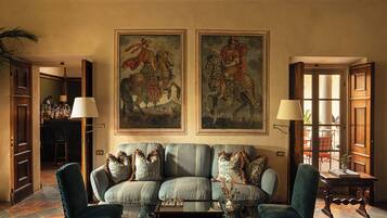 Sala de estar com sofá, duas poltronas, uma mesa de centro e um quadro de um cavaleiro.
