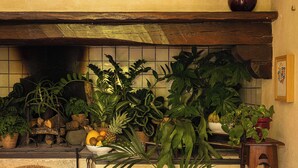 A kitchen with a tiled backsplash, wooden beams, and various potted plants.