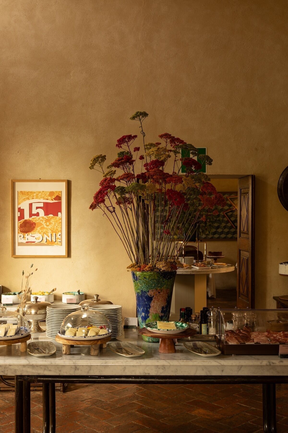 A buffet setup with various food items and a large decorative vase with flowers.