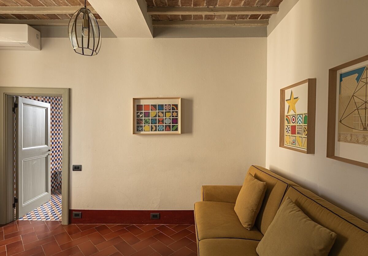 Una habitación con suelo a cuadros, un sofá, un cuadro enmarcado y una lámpara en el techo.