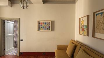 Una habitación con suelo a cuadros, un sofá, un cuadro enmarcado y una lámpara en el techo.