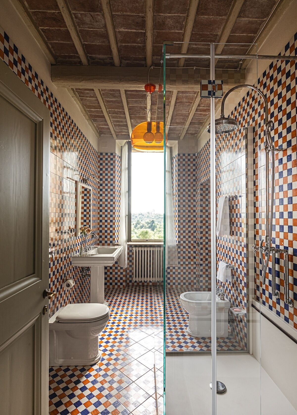 A bathroom with checkered tile flooring, a white sink, a toilet, and a shower area.