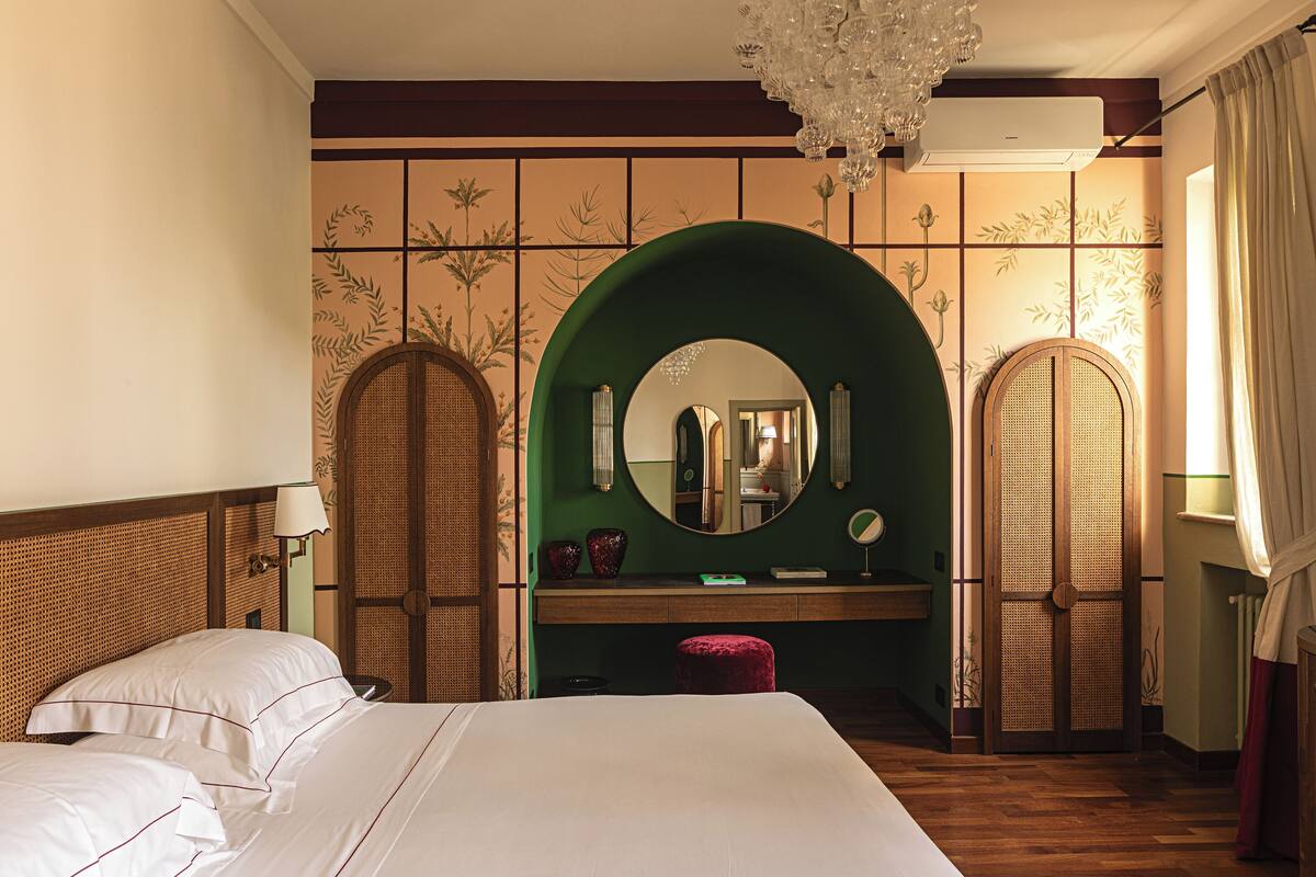 Una habitación de hotel con una cama grande, un tocador con espejo y un arco verde.