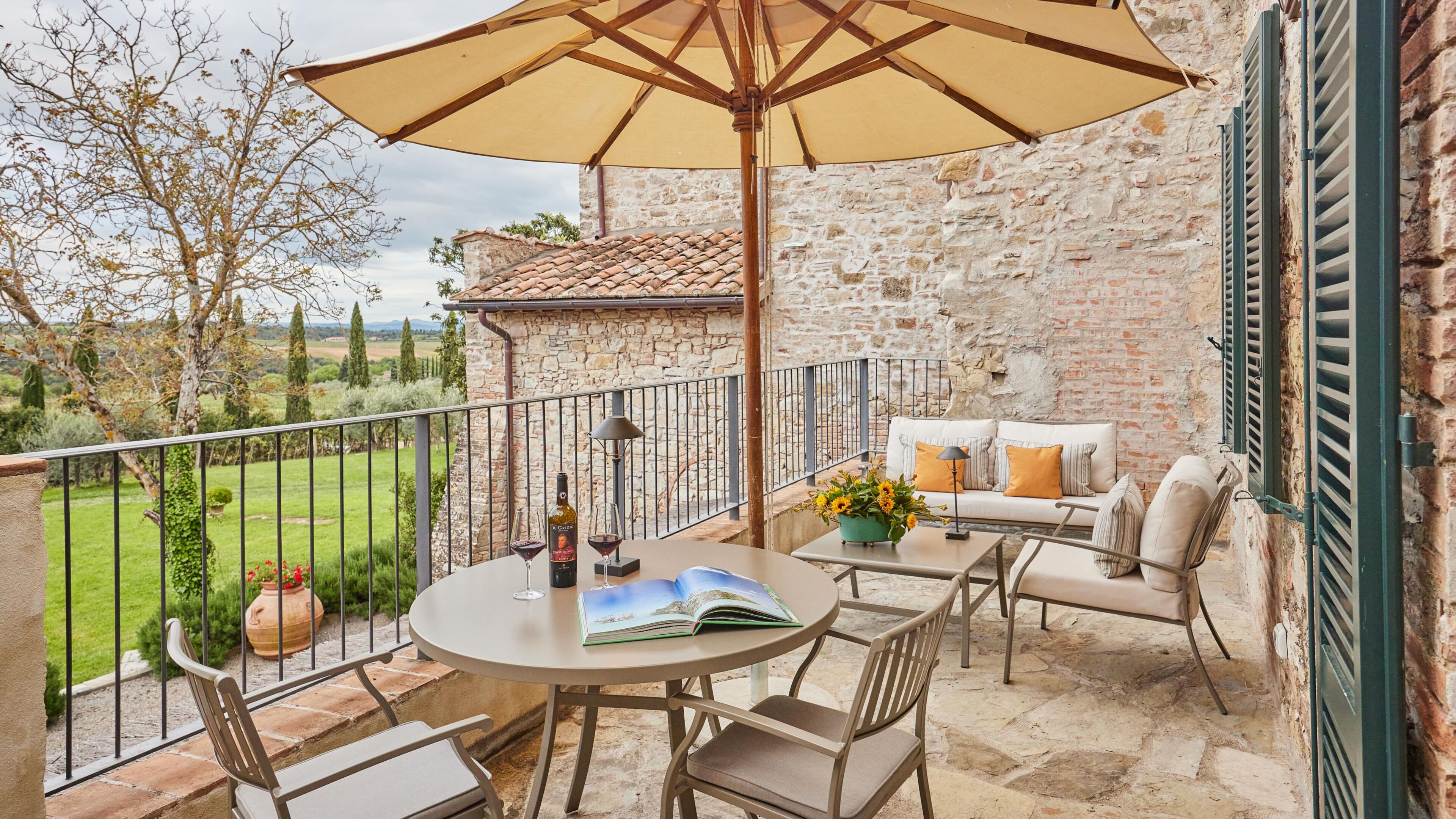 A terrace with a table, chairs, a wine bottle, and a book.
