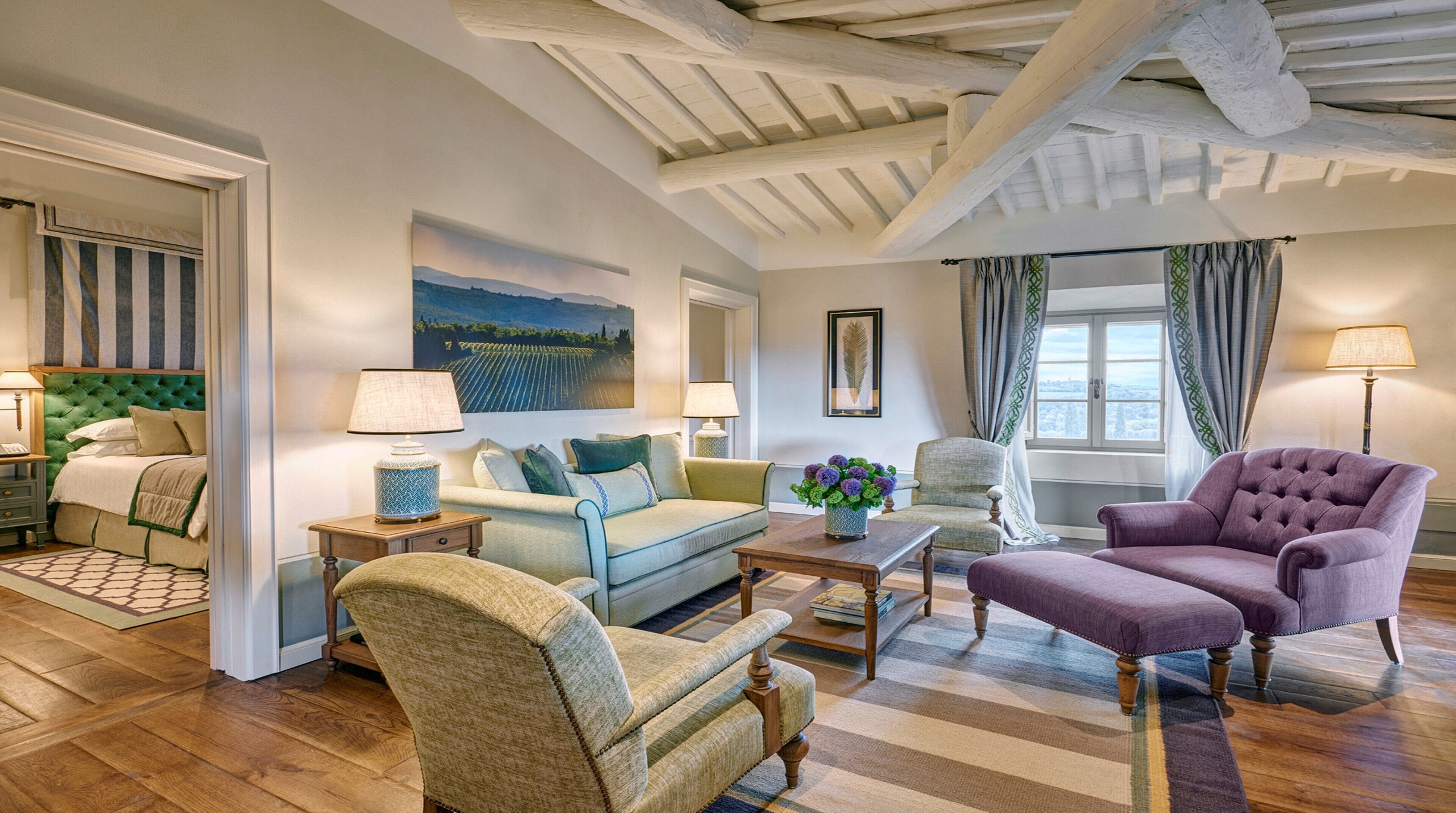A spacious living room with a sofa, armchairs, a coffee table, and a painting on the wall.