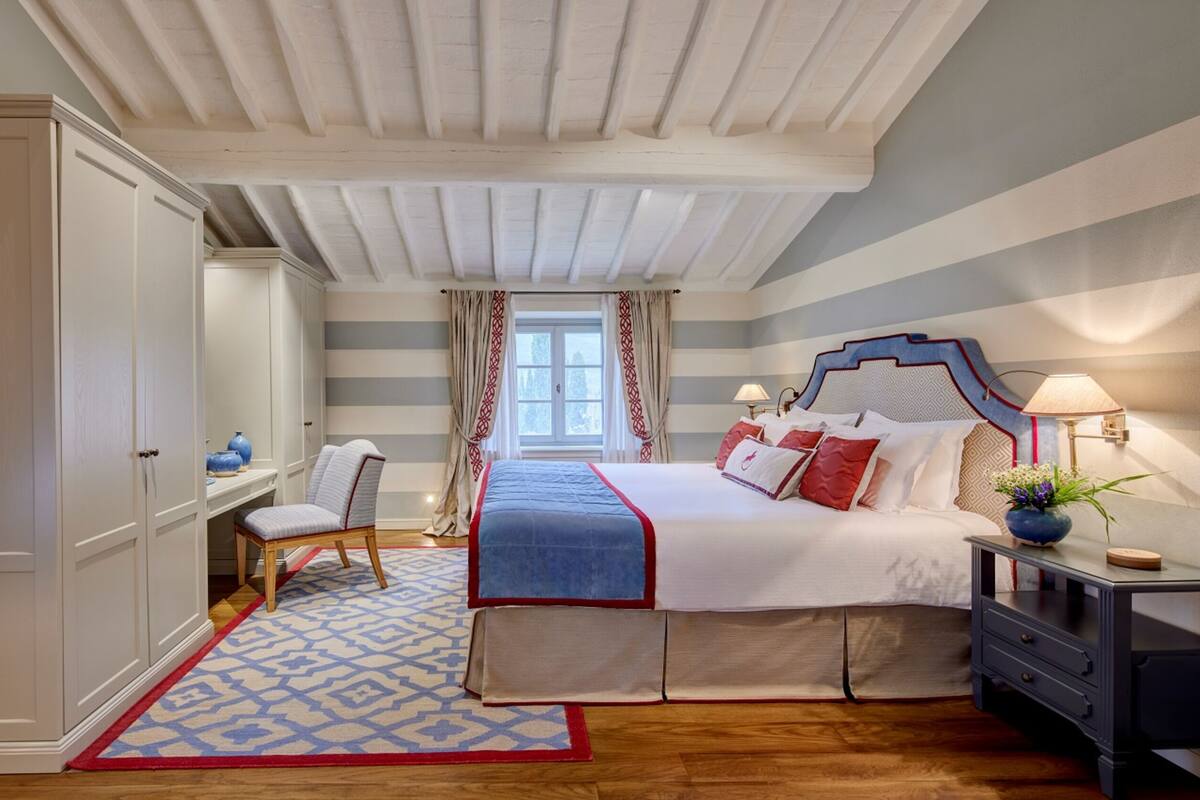 Ein Schlafzimmer mit einem großen Bett, einem Sessel, einem Schreibtisch und einem Kleiderschrank.