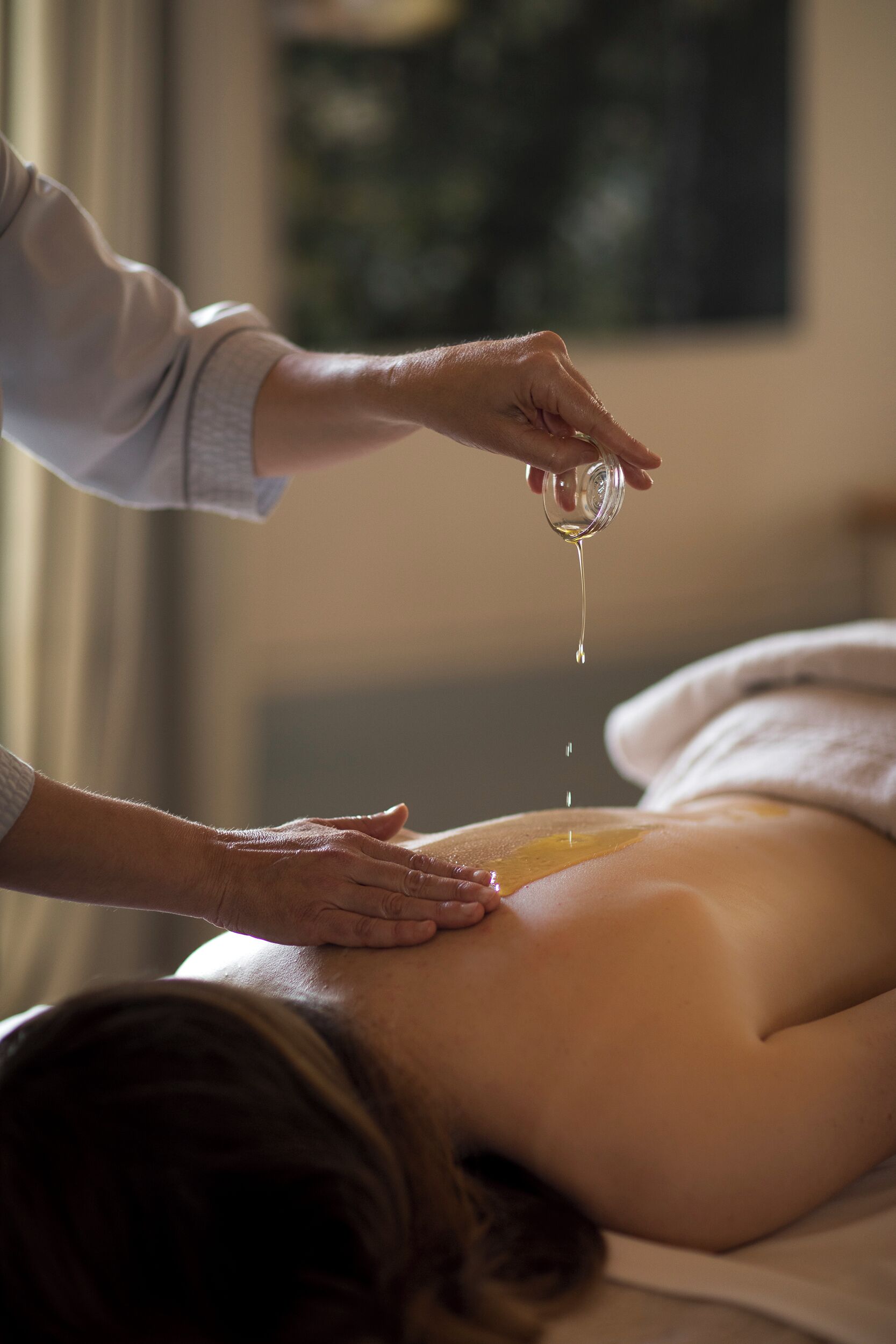 Une personne reçoit un massage du dos, et une pipette est utilisée pour appliquer de l’huile.