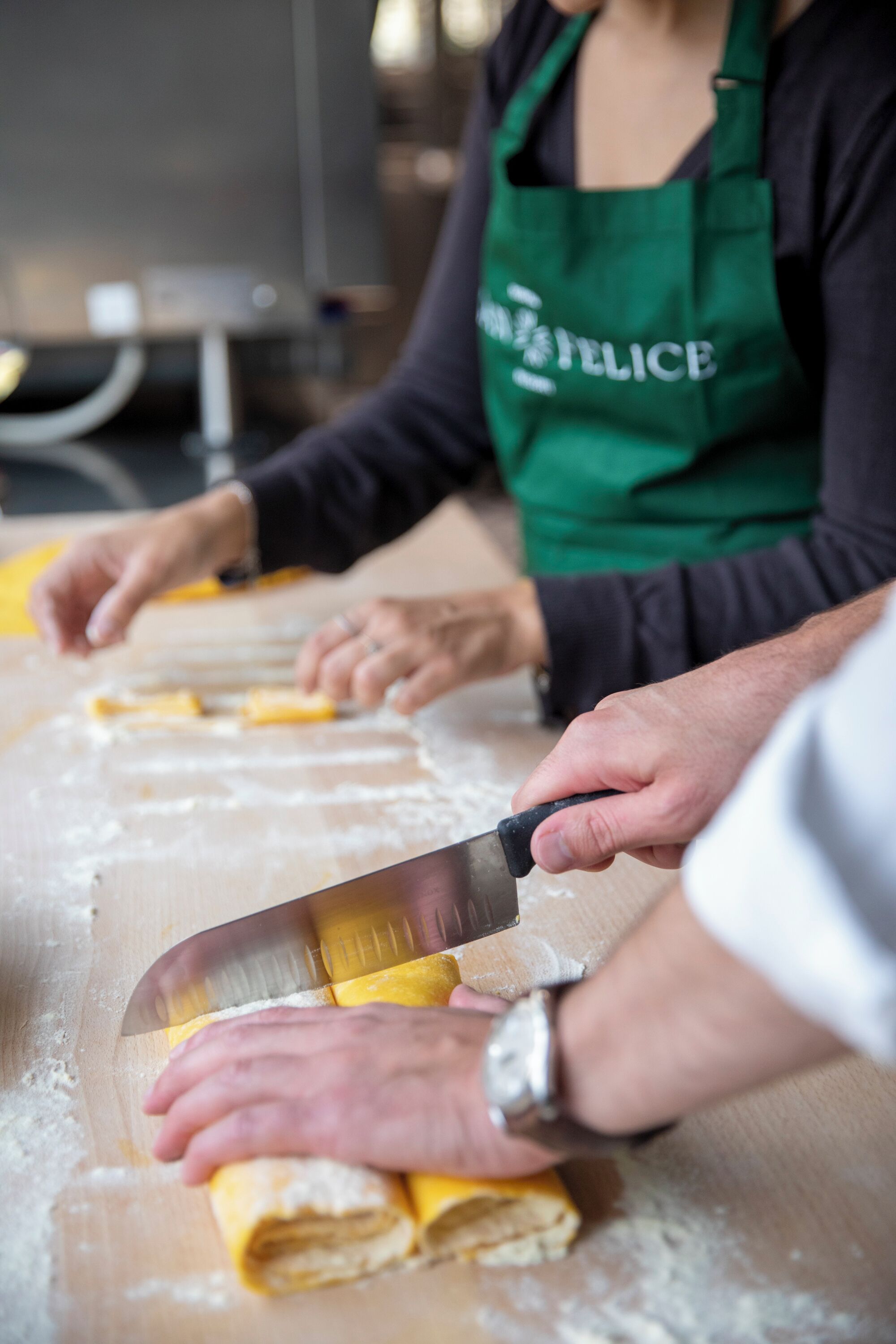 A person rolling dough on a wooden surface.