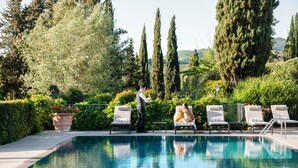 Un espace piscine équipé de chaises longues et où un membre du personnel est à la disposition des clients.