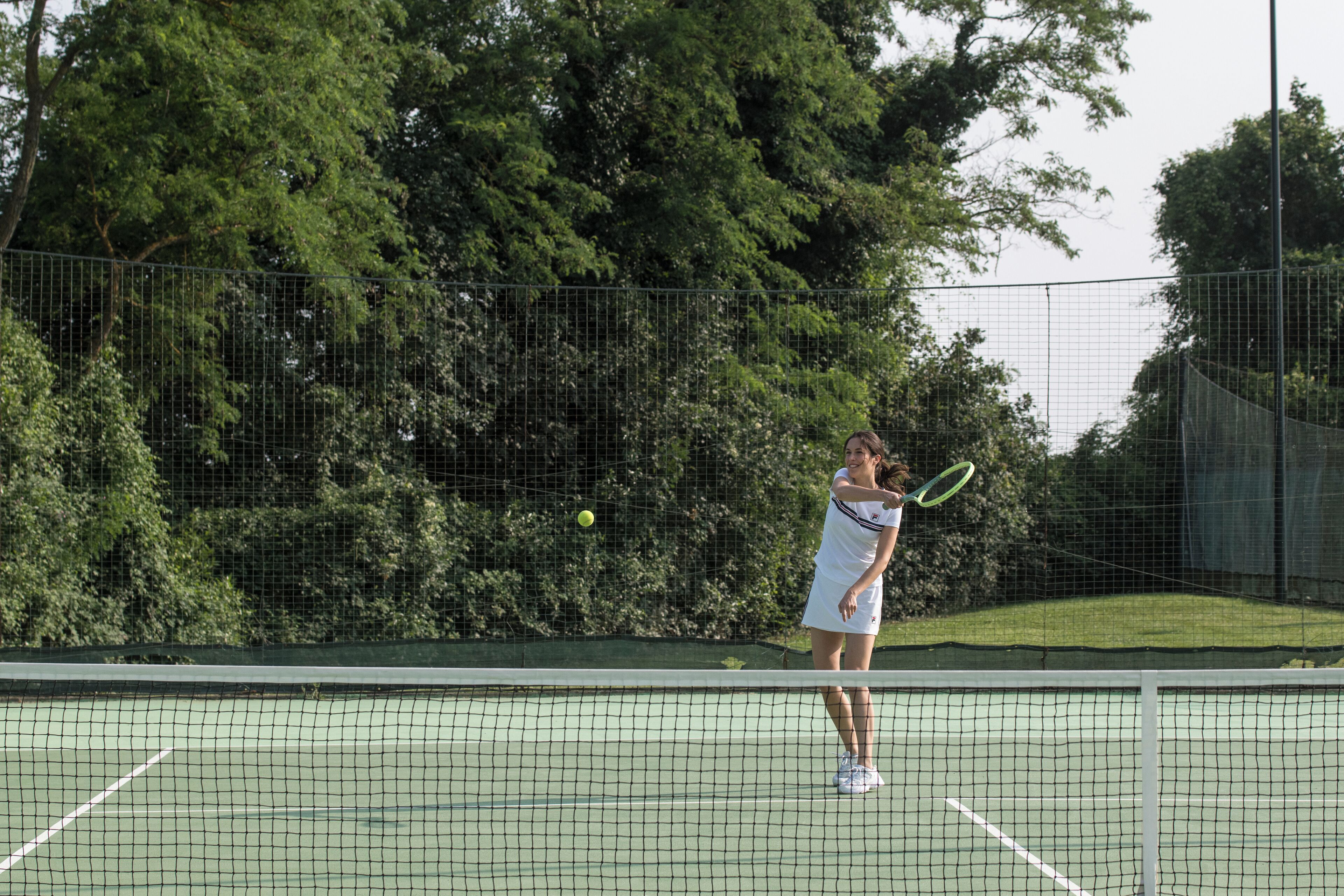 Ein Tennisplatz mit Netz, umgeben von Bäumen.