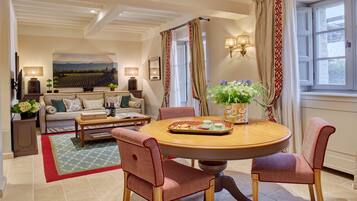 A well-furnished living room with a round dining table, red patterned chairs, a sofa, and a coffee table.