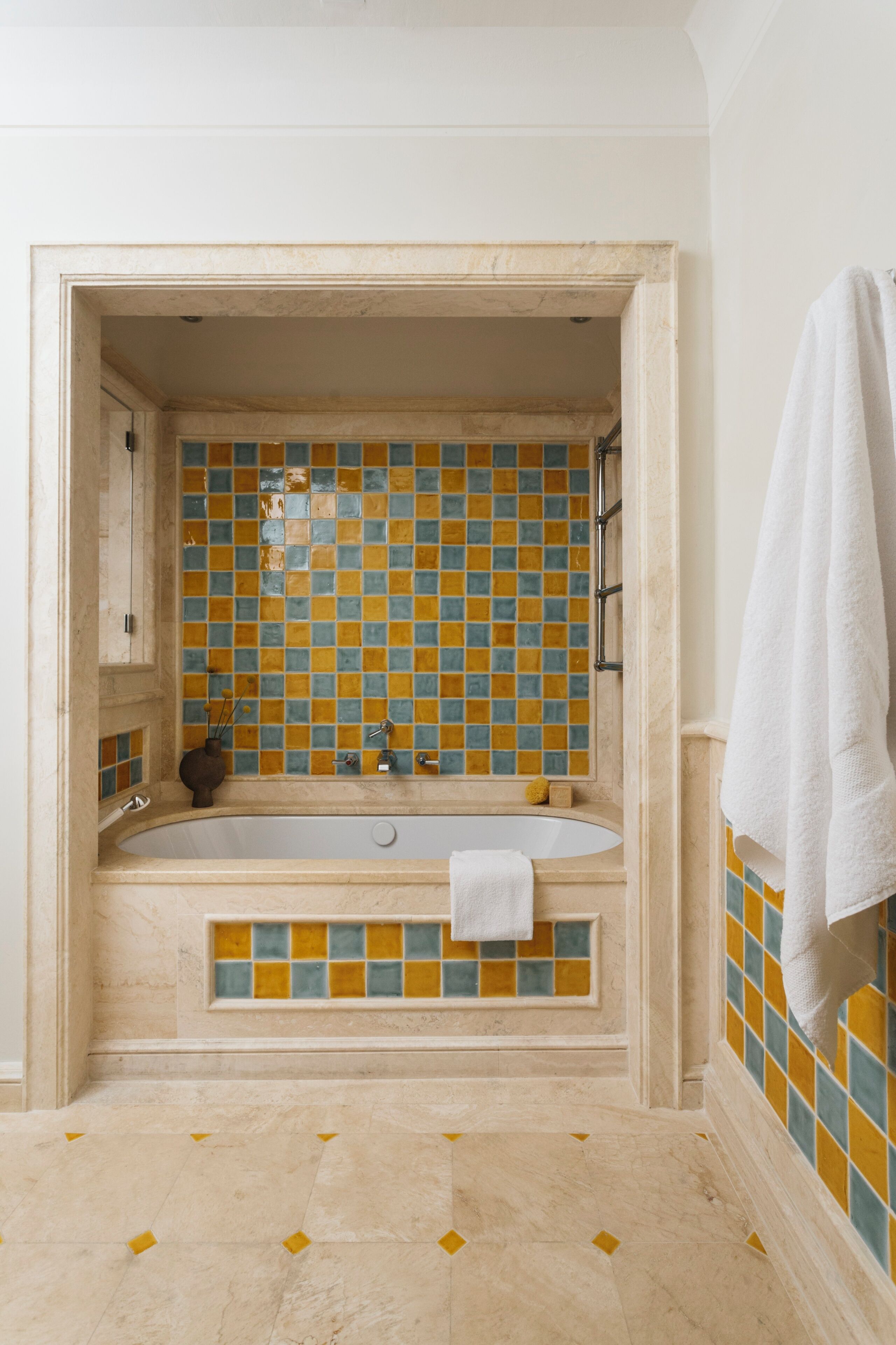 A bathroom with a bathtub, tiled walls, and a towel hanging on the wall.